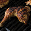 A close-up of a grilled chicken leg on a black grill.
