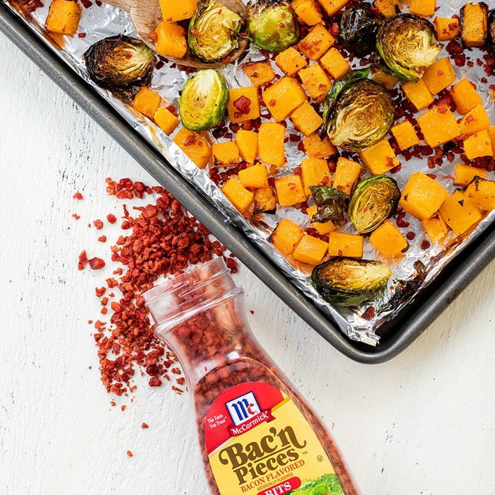 A baking sheet with roasted butternut squash and brussels sprouts, sprinkled with McCormick Bac'n Pieces.