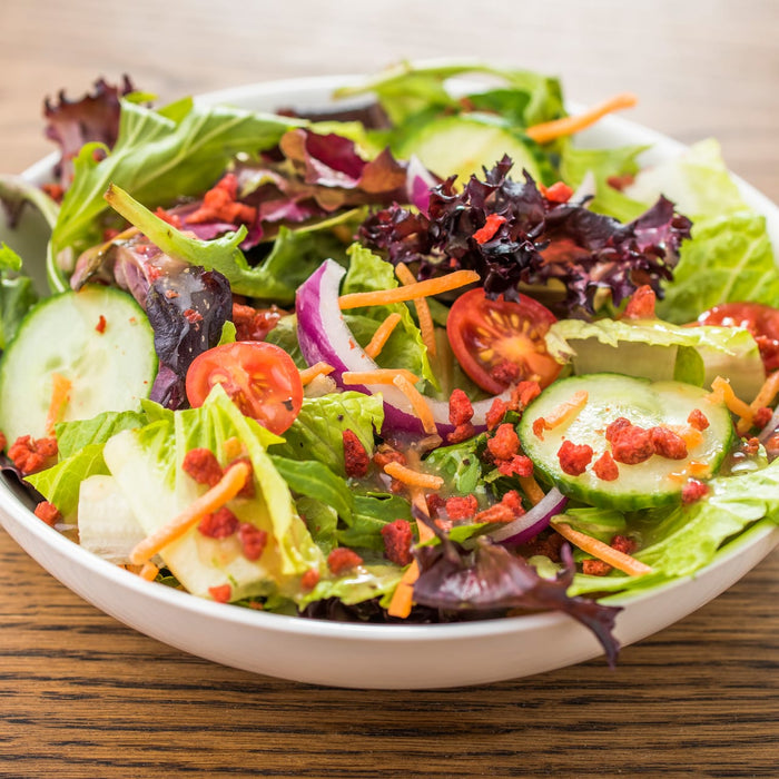 A bowl of salad with cucumbers, tomatoes, red onion, and croutons.
