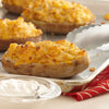 Baked potatoes with cheese and sour cream on a baking sheet.