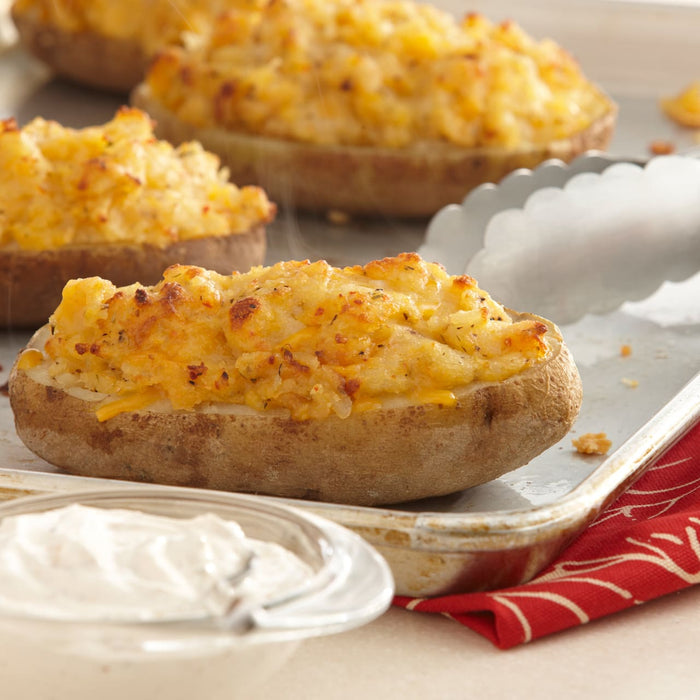 Baked potatoes with cheese and sour cream on a baking sheet.