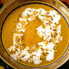 A bowl of pumpkin soup with cream and pumpkin seeds.