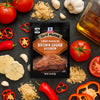 A packet of McCormick Grill Mates Brown Sugar Bourbon seasoning is displayed amidst fresh ingredients like tomatoes, garlic, peppers, and brown sugar, suggesting a flavorful grilling experience.