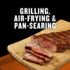 A juicy steak cooked using grilling, air-frying, and pan-searing methods is displayed on a wooden cutting board.