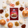 A packet of McCormick Chili seasoning is surrounded by fresh ingredients like onions, garlic, and chili peppers.