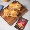 Two delicious sandwiches made with McCormick Chicken Gravy are displayed on a wooden board.
