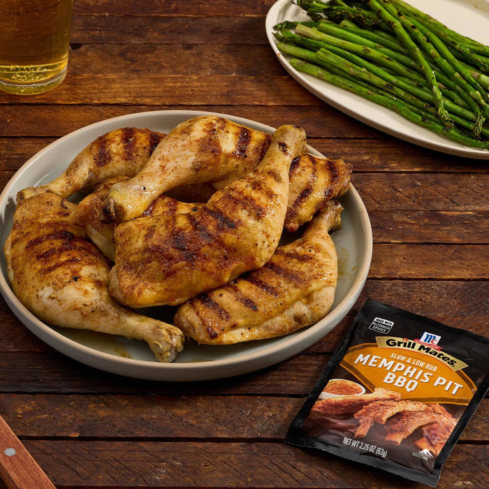 A plate of grilled chicken legs seasoned with McCormick's Kentucky Pit BBQ seasoning, accompanied by asparagus.