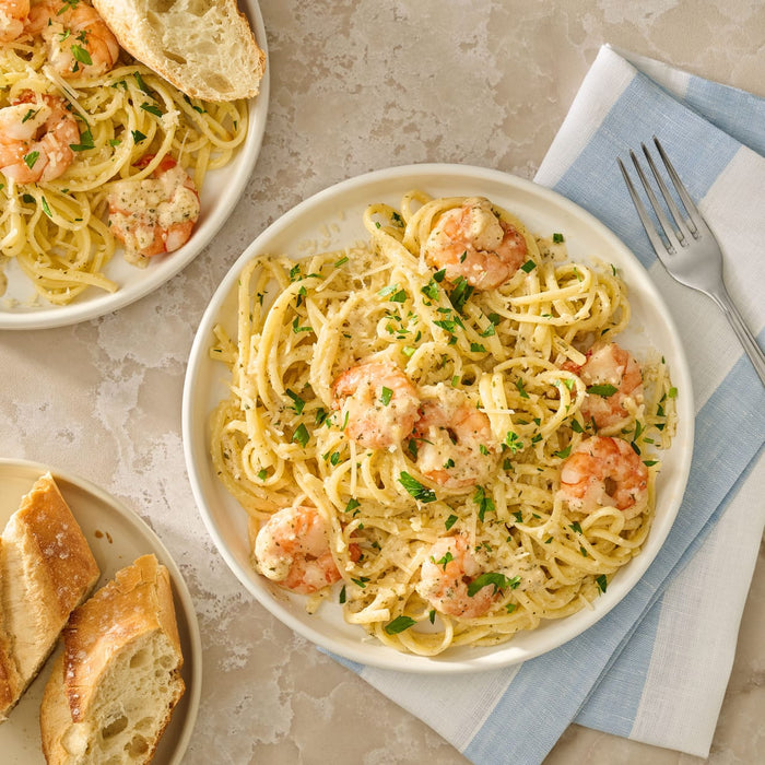 A close up view of restaurant style scampi featuring linguine pasta and shrimp prepared with Mccormick Garlic Butter Shrimp Scampi Seasoning Mix .87 Oz and topped with fresh parsley and parmesan cheese.
