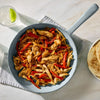A skillet of chicken fajita ingredients with a package of McCormick Fajita seasoning mix and a finished fajita on a plate.