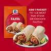A close-up of a skillet of fajita ingredients with a McCormick Fajita seasoning packet.