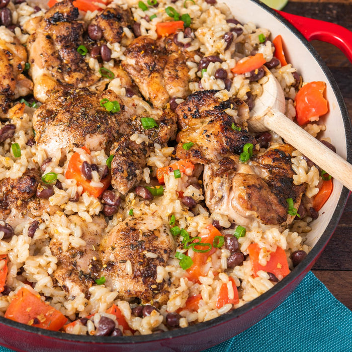 A close-up of a skillet filled with chicken, rice, black beans, and tomatoes.