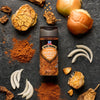 A bottle of Schwartz Chicken Seasoning is surrounded by ingredients like garlic, onion, and paprika.