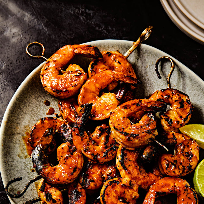 A plate of grilled shrimp skewers with lime wedges showcasing a delicious and visually appealing seafood dish.