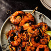 A plate of grilled shrimp skewers with lime wedges showcasing a delicious and visually appealing seafood dish.