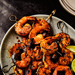 A plate of grilled shrimp skewers with lime wedges showcasing a delicious and visually appealing seafood dish.
