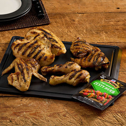 A platter of grilled chicken pieces, including wings, drumsticks, and breast, is displayed with a packet of Jack Link's jerky.