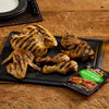 A platter of grilled chicken pieces, including wings, drumsticks, and breast, is displayed with a packet of Jack Link's jerky.