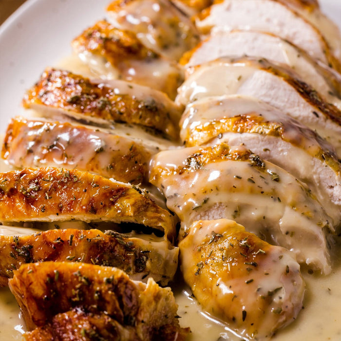 Sliced roasted turkey with gravy, showcasing a delicious and savory meal.