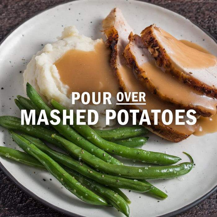 A plate of sliced turkey breast, mashed potatoes with gravy, and green beans.