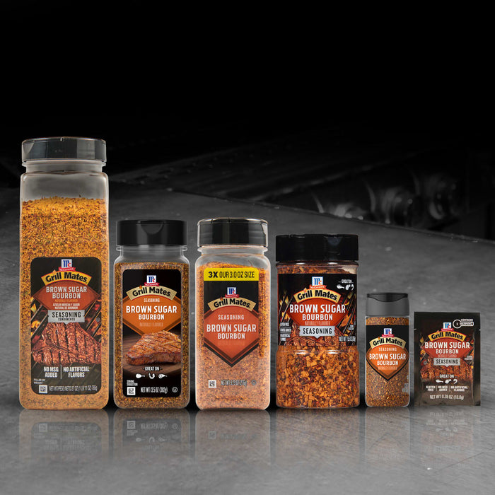 A lineup of McCormick Grill Mates Brown Sugar Bourbon seasoning products in various sizes and packaging, featuring the Mccormick Grill Mates Brown Sugar Bourbon Blend Gf 3.0 Oz, arranged on a reflective surface.