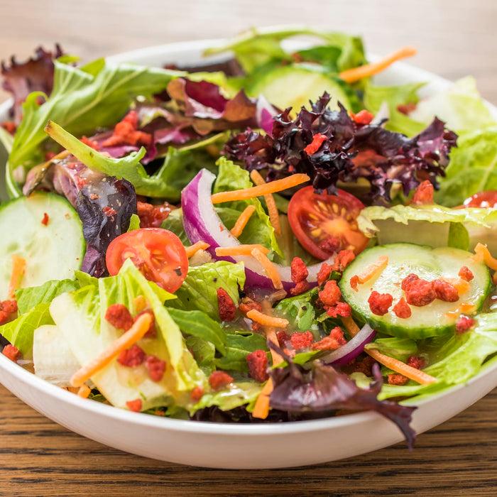 A bowl of salad with cucumbers tomatoes red onion and carrots.