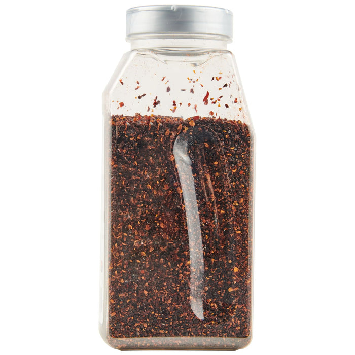 A clear plastic shaker bottle containing Mccormick Culinary Crushed Chipotle Pepper stands upright with a silver cap.