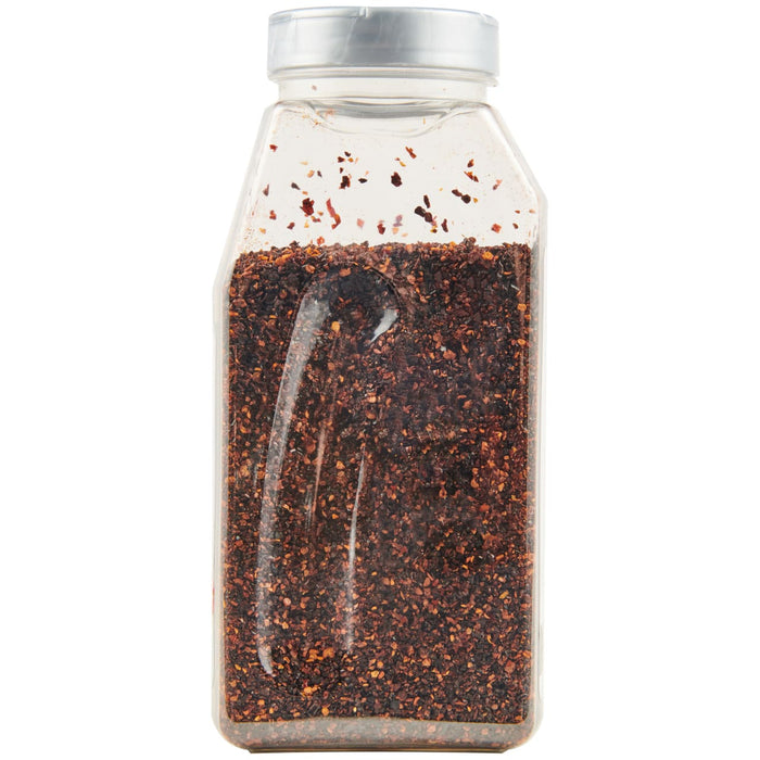 A clear plastic bottle filled with dried red pepper flakes.