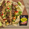 Grilled skewers of meat, pineapple, and red pepper are seasoned with McCormick Brazilian Churrasco seasoning and garnished with lime wedges and cilantro.