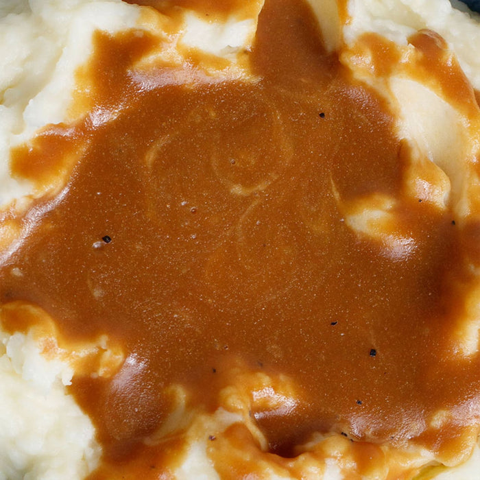 A plate of roast beef with mashed potatoes asparagus and gravy.