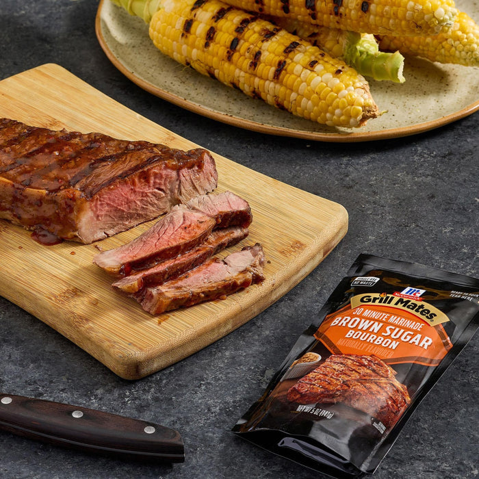 A grilled steak sliced on a wooden board, served with corn on the cob and McCormick Brown Sugar Bourbon seasoning.