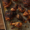 A tray of freshly baked, richly spiced chicken pieces with a dark, flavorful crust.
