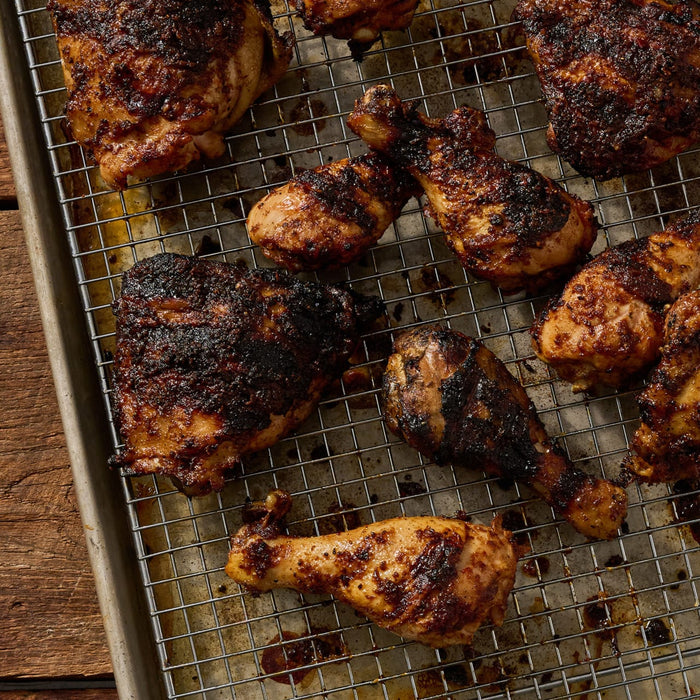 A tray of freshly baked, richly spiced chicken pieces with a dark, flavorful crust.