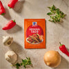 A vibrant orange and red packet of Mccormick Taco Seasoning Mix featuring two prepared tacos on the front, surrounded by fresh onions, garlic, and red bell peppers.