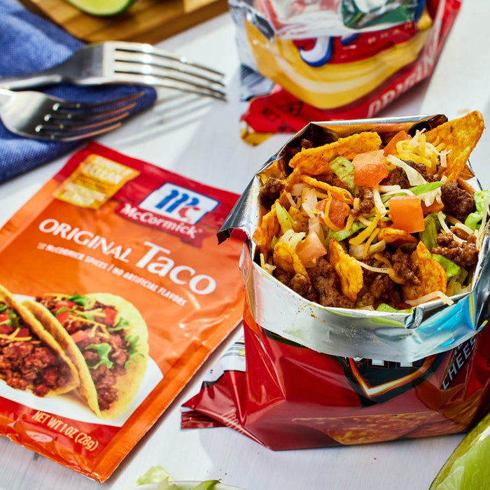 A bag of McCormick Original Taco seasoning next to a bag of tortilla chips filled with ground beef lettuce tomatoes and cheese.
