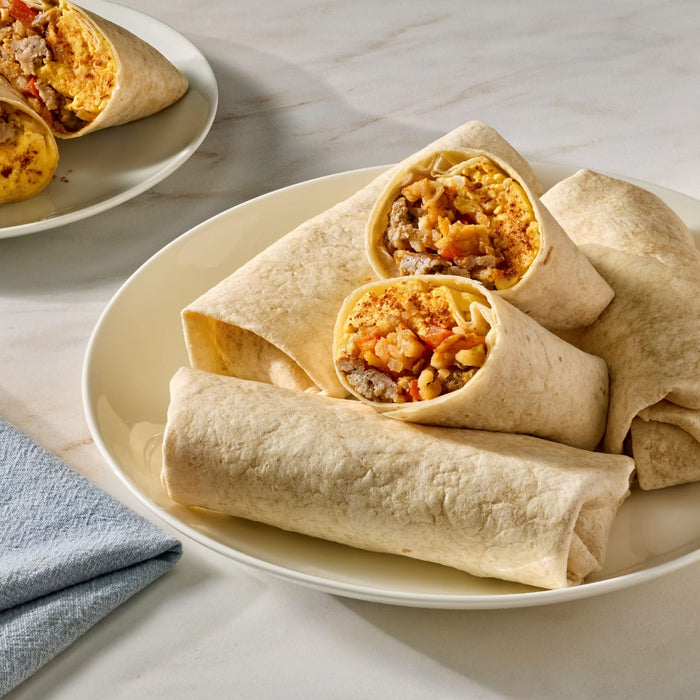 A packet of Mccormick Taco Seasoning Mix is displayed next to a walking taco served in a chip bag, with forks and lime in the background.