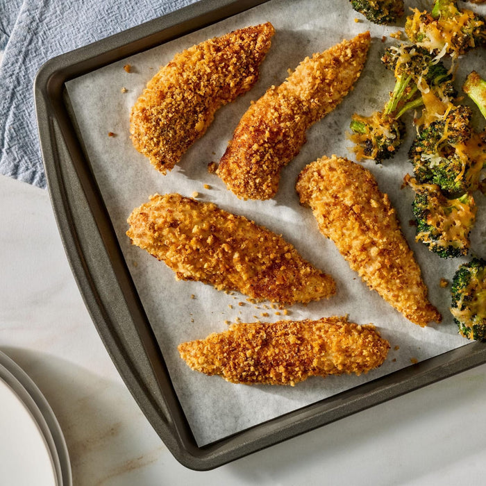 Crispy chicken tenders and cheesy broccoli on a gray plate are accompanied by a package of Mccormick Taco Seasoning Mix in the foreground.