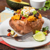 A baked sweet potato topped with black beans avocado sour cream and spices.