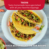 Three homemade hard-shell tacos, seasoned with Mccormick Organics Regular Taco Seasoning Mix 1 Oz, are presented on a white plate with toppings like lettuce, cheese, and tomatoes.