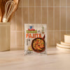 A packet of Mccormick Organics Regular Fajita Seasoning Mix 1 Oz sits on a kitchen counter in front of a tiled backsplash, with kitchen utensils and plates nearby.
