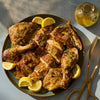 A plate of spatchcocked chicken with lemon wedges, ready to be served.