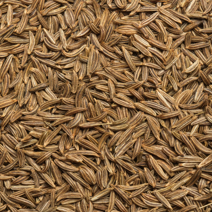 A close-up of whole cumin seeds, showcasing their elongated shape and brown color.