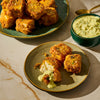 A plate of golden fried paneer cheese cubes is served with a creamy green dipping sauce.