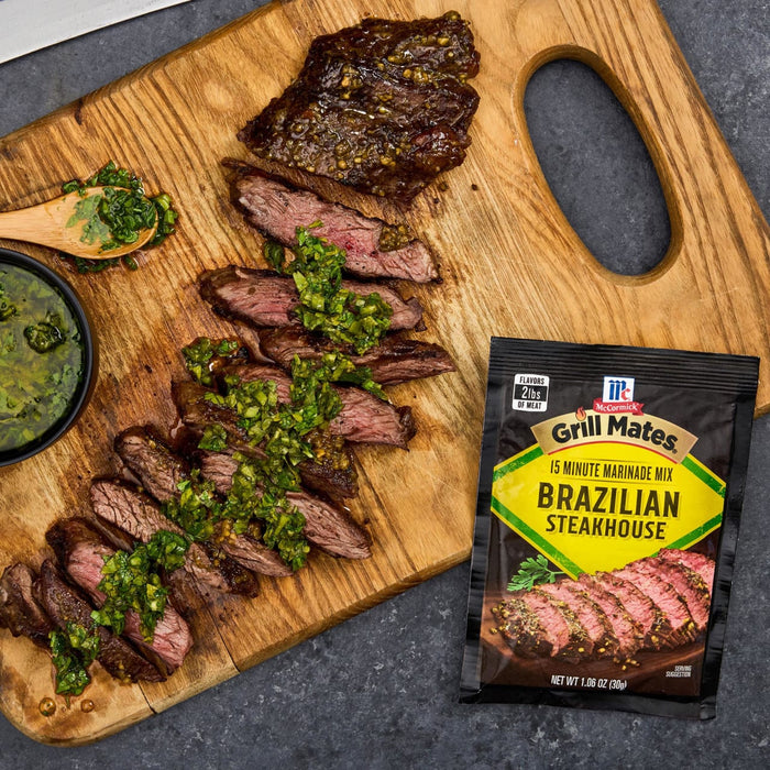 A sliced steak seasoned with McCormick Grill Mates Brazilian Steakhouse seasoning is displayed on a wooden cutting board with a side of green sauce.