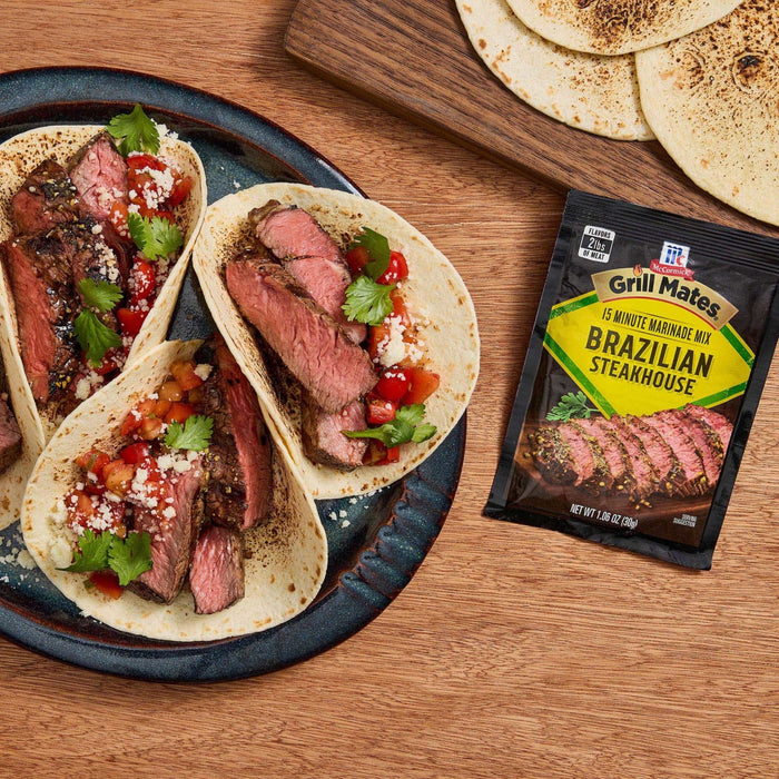 Three tacos filled with grilled steak and salsa are displayed next to a packet of McCormick Grill Mates Brazilian Steakhouse seasoning.