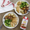 Two plates of chicken broccoli and potatoes with McCormick Simply Better Chicken Gravy are displayed on a wooden table.