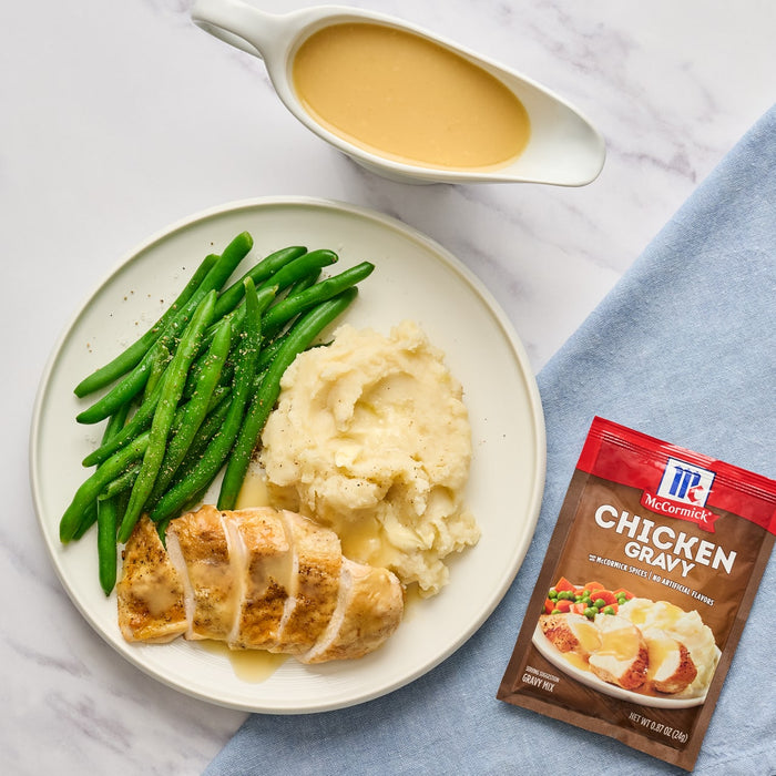 A plate of chicken mashed potatoes and green beans with McCormick Chicken Gravy mix packet.