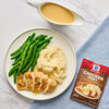 A plate of chicken mashed potatoes and green beans with McCormick Chicken Gravy mix packet.