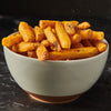 A bowl of golden french fries is seasoned with salt and pepper.
