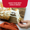 A hand pulls a cheesy slice of pull-apart bread seasoned with Mccormick Garlic And Herb Pepper Seasoning Ground 4.37 Oz from a wooden board.