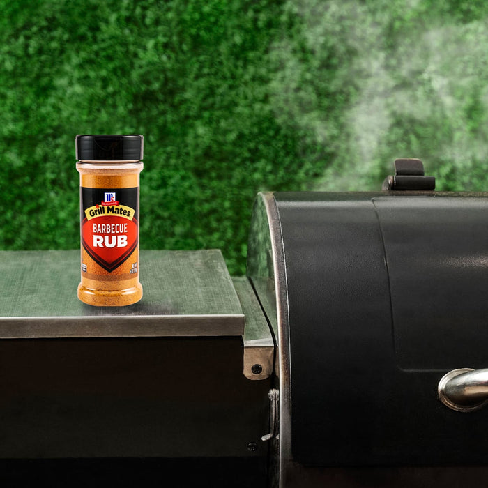 A bottle of McCormick Grill Mates BBQ Rub sits on a grill, suggesting a delicious barbecue experience.